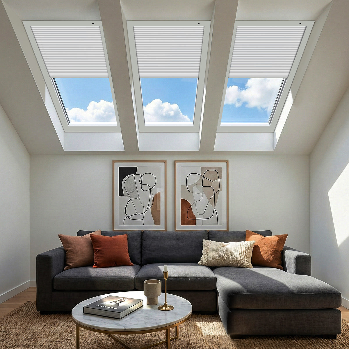 Three white motorized blackout cellular shades partly closed on skylights above a grey sectional sofa in a bright living room
