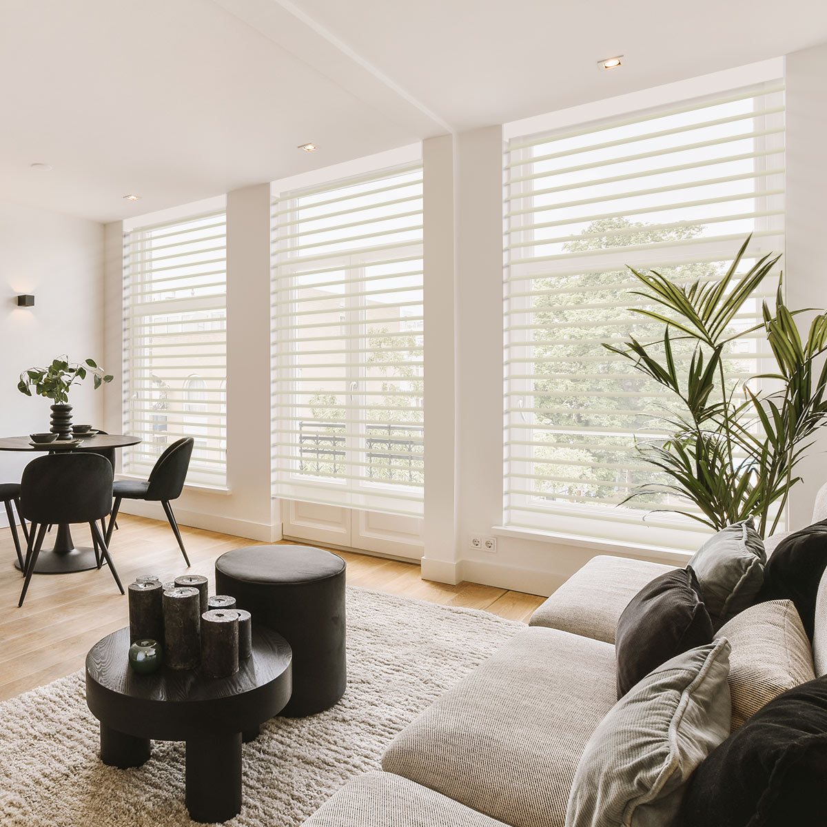 Cream light filtering motorized sheer shades lowered across tall windows in a bright living room