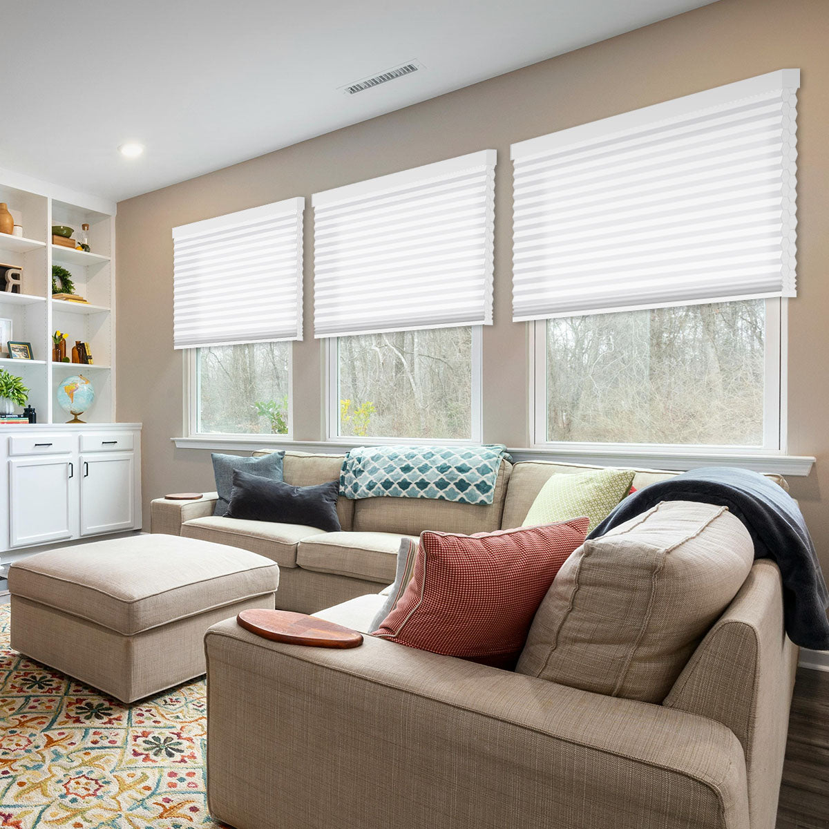 White double cell light filtering cellular shades on three large living room windows above a sectional sofa