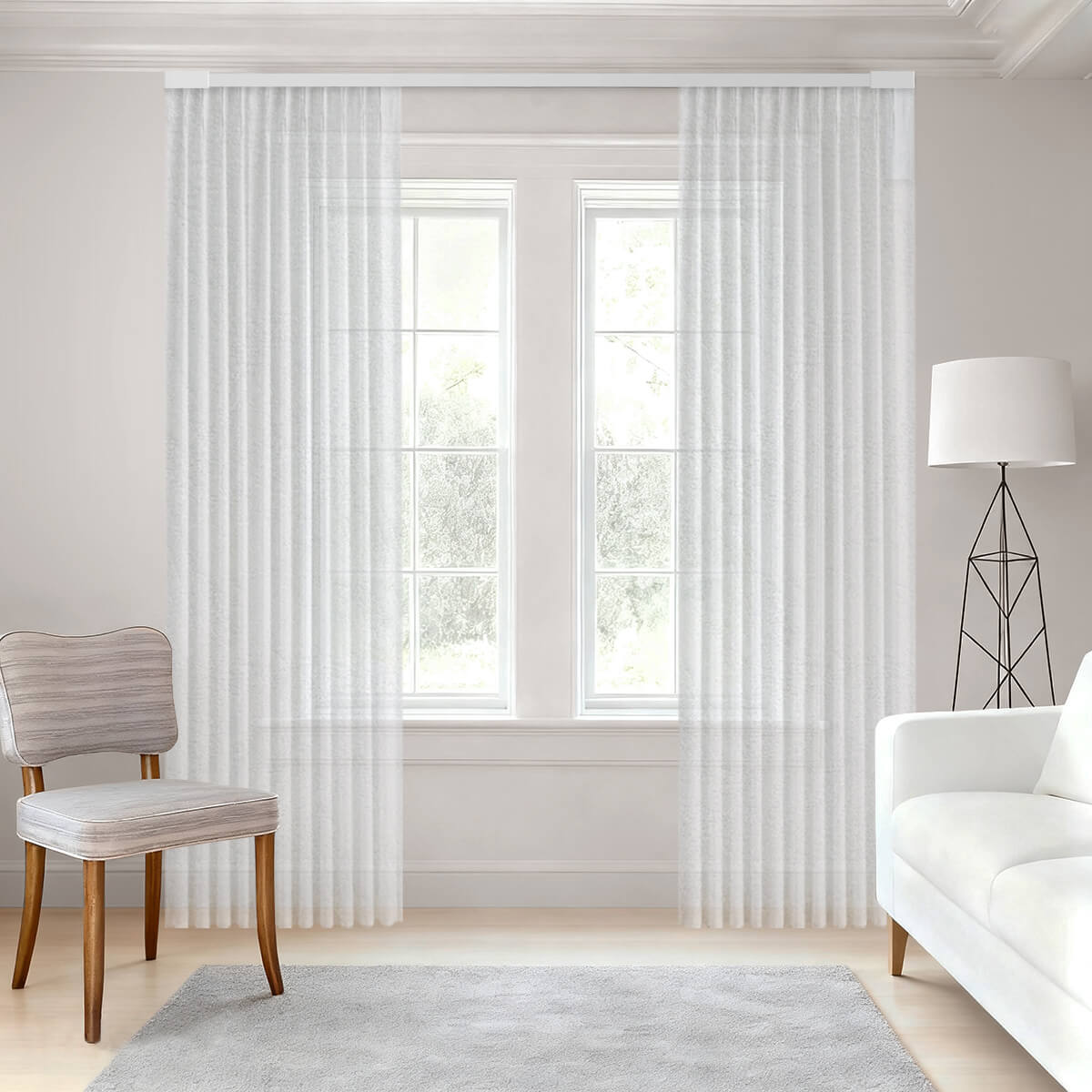 Bright room with floor-length white sheer drapes softly filtering daylight between a floor lamp, a white sofa and a striped chair