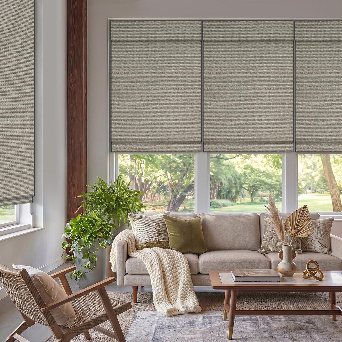 Linen Mist Grey woven wood shades lowered over living room windows above a beige sofa and plants