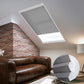 Skylights with blinds above a cozy bed, set against a warm-toned exposed brick wall.