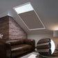 Skylights with blinds above a cozy bed, set against a warm-toned exposed brick wall.
