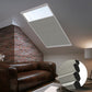 Skylights with blinds above a cozy bed, set against a warm-toned exposed brick wall.