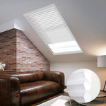 Skylights with blinds above a cozy bed, set against a warm-toned exposed brick wall.