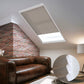 Skylights with blinds above a cozy bed, set against a warm-toned exposed brick wall.